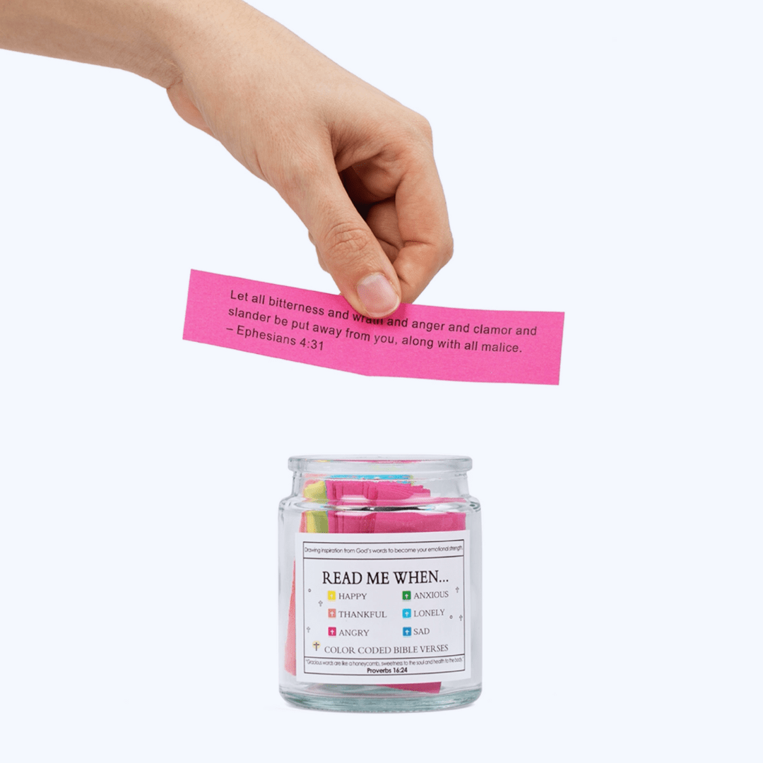 Hand placing a pink Bible verse card into the Bible Verse Jar