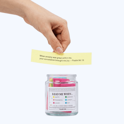 Hand placing a yellow Bible verse card into the Bible Verse Jar